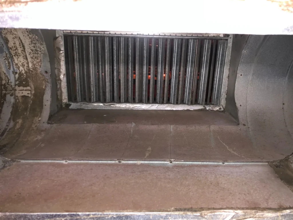 Commercial supply plenum with debris on the floor before cleaning