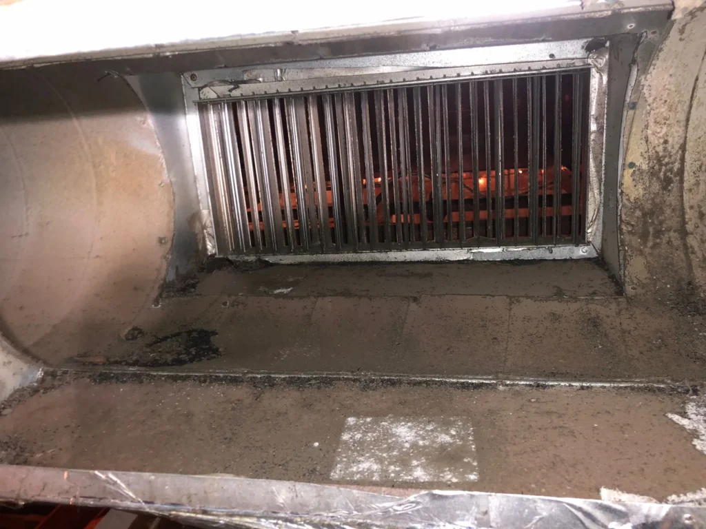 Debris along the floor of a commercial supply plenum before cleaning