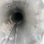 Dryer vent duct being cleaned with a rotary brush