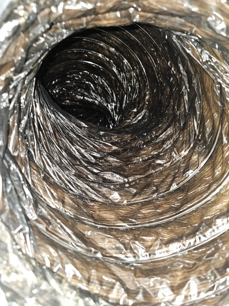 Dust and debris lining a flex air duct before cleaning