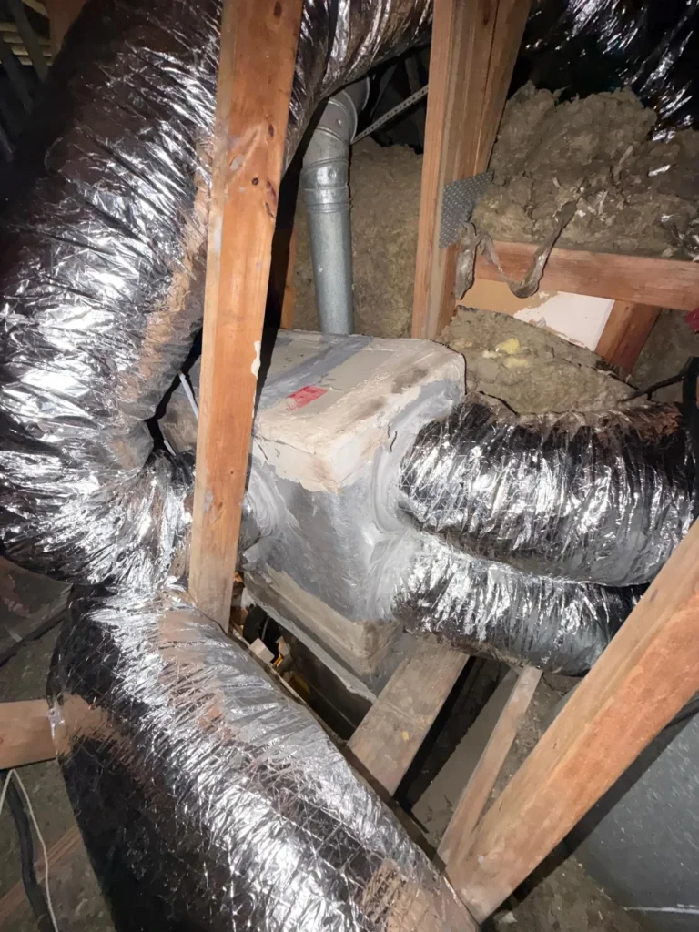 Old flex duct runs in a home attic before replacement