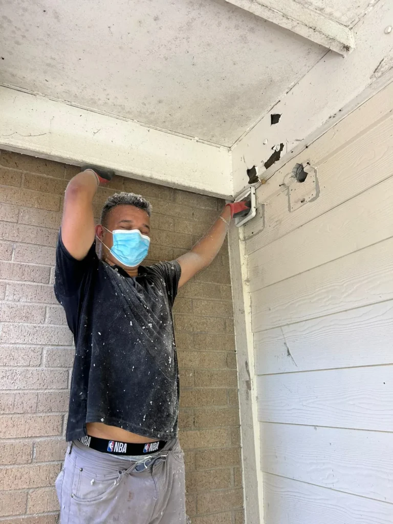 Technician cleaning a dryer vent at the exterior wall of a home