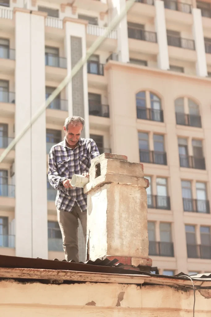 Worker repairing a chimney on a roof